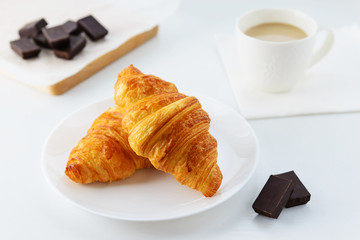 Croissants with a cup of coffee on a white table