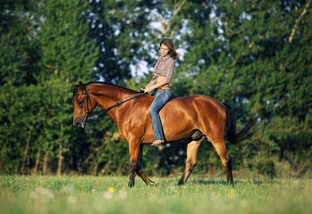 Obraz na płótnie Canvas Beautiful cowgirl bareback ride her horse in woods glade at sunset