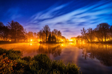 Park in Pszczyna, Poland on a starry night with gentle clouds and stars visible.