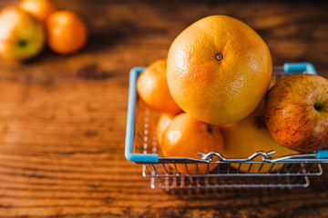 healthy orange-coloured fruit in mini shopping basket