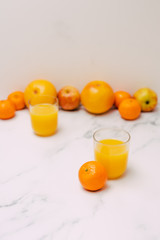 healthy fruit including oranges grapefruits and apples scattered on light-toned marble and with...