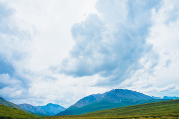 Spectacular view of giant mountains under cloudy sky. Huge mountain range at overcast weather. Wonderful wild scenery. Atmospheric dramatic highland landscape of majestic nature. Scenic mountainscape.