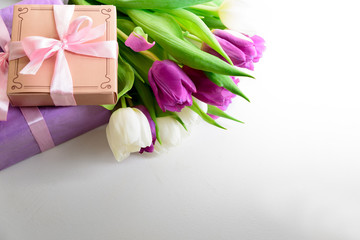 Bouquet of white and purple tulips and gift box on white wooden background. Top view. Flat lay. Copy space. Valentines day, mothers day, birthday, wedding celebration concept.