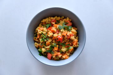 Healhty vegan bowl with quinoa, pumpkin, pepper and carrot on gray wooden background. Selective focus
