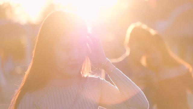 Beautiful Asian girl smile in the sunshine. Royalty high-quality stock video footage of a pretty Asia young woman with long hair nice smiling in sun light backlit. Beautiful girl in sunlight backlight