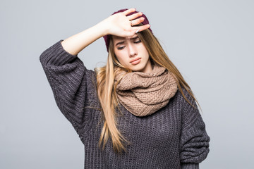 Young woman has a cold and a headache in warm hat isolated on gray background