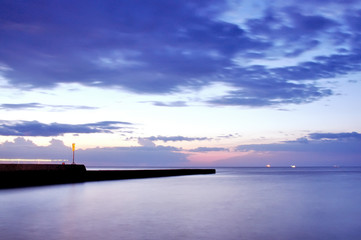 The sea in the early morning until dawn. Pier and sullen sky. Long exposure.
