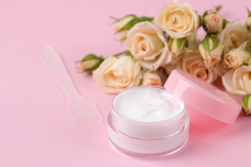 Fototapeta na wymiar cosmetics for face and body in pink bottles with fresh roses on a delicate pink background. cream and lotion. spa.