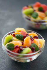 Bowl of healthy fresh fruit salad on black background.