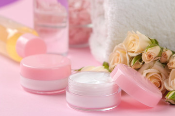 Fototapeta na wymiar cosmetics for face and body in pink bottles with fresh roses on a delicate pink background. cream and lotion. spa.