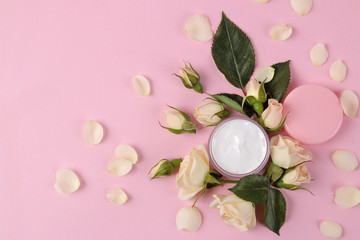 cosmetics for face and body in pink bottles with fresh roses on a delicate pink background. cream in rosebuds. spa. top view