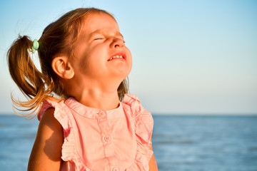 Portrait of crying little cute girl on the beach