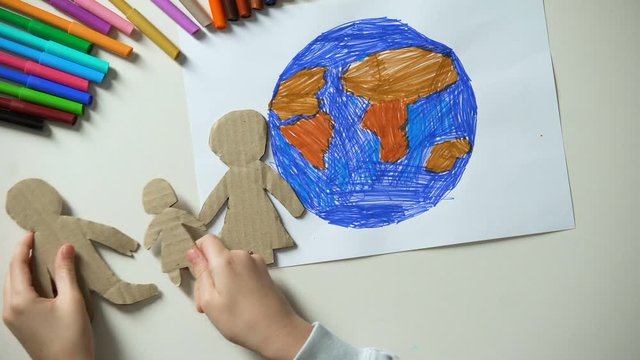 Child putting paper family and heart sign near Earth painting, saving planet