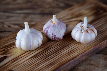 Garlic lies on a wooden chopping Board.