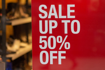 Red sign Sale up to 50 percentage off in shop window display