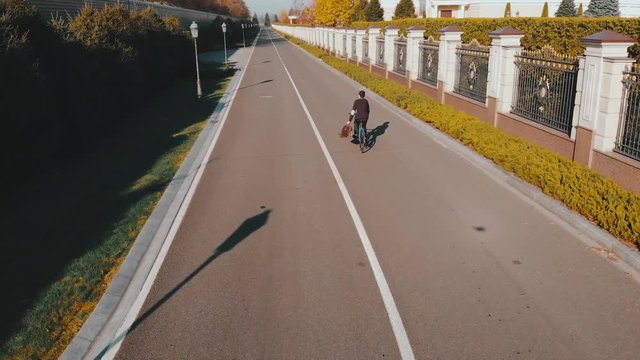 aerial fly above men on cycle ryding strong direction on road, 4k, Mezhyhirya Residence, Ukraine