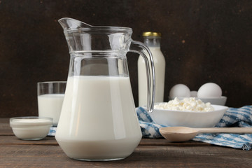 milk products. milk, sour cream, cheese, butter and cottage cheese on a brown wooden table