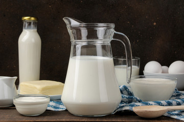 milk products. milk, sour cream, cheese, butter and cottage cheese on a brown wooden table