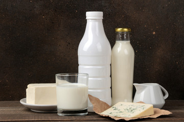 milk products. milk, sour cream, cheese, butter and cottage cheese on a brown wooden table