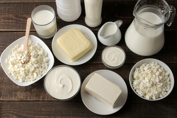 milk products. Milk, sour cream, cheese, butter and cottage cheese on a brown wooden table. top view