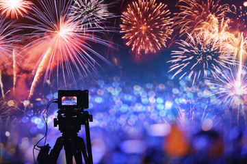 back side silhouette digital camera on tripod recording beautiful fireworks for celebrate in low...