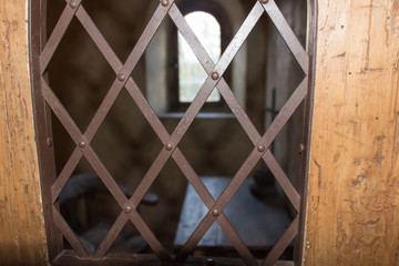 Ancient prison cell. View through a window with an iron grid.