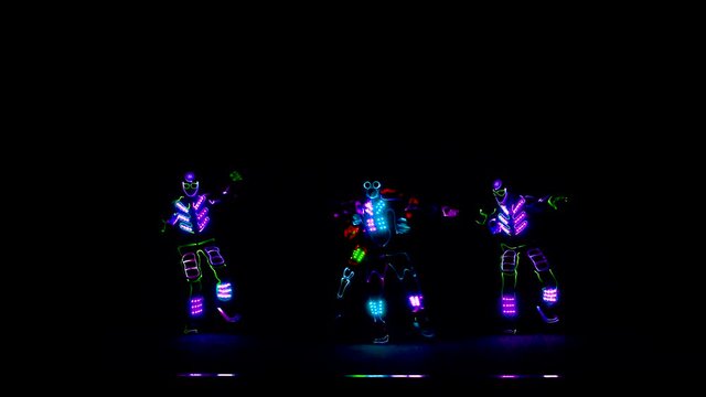 4 people dancing in costumes of LEDs
