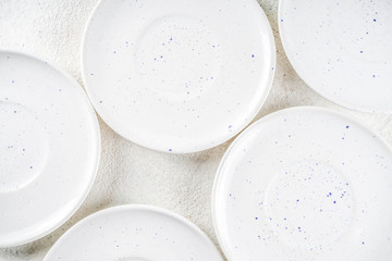 Assortment stack clean empty new white kitchen utensils, plates, bowls, cups mugs. On a white concrete background