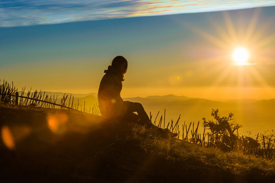 silhouette of lonely female traveler with  beautiful sunrise and mountains with blue sky  in the morning, chiang mai in thailand