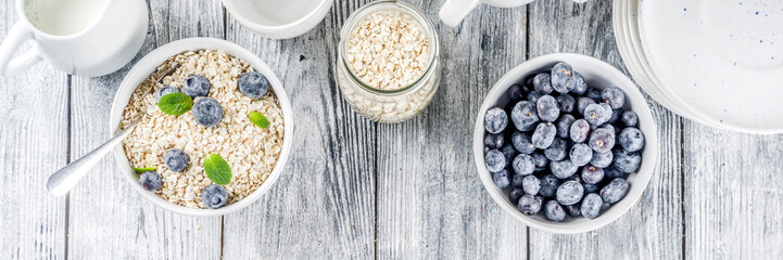Healthy cereal and milk breakfast concept, dry oats in small bowl, with milk and fresh blueberry,...