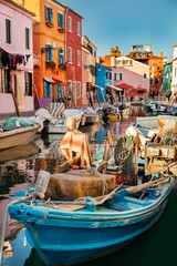 Burano island picturesque street with small colorful houses, smal water canal with beautiful reflections and  boats, Venice Italy  - obrazy, fototapety, plakaty