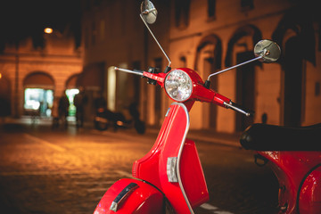Red Scooter parked on  the old street in Rome, Italy. Night time