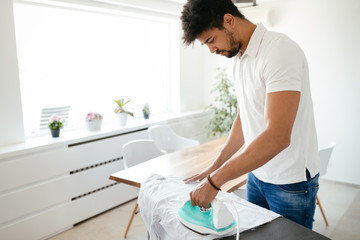 Young Happy Man Ironing Clothes