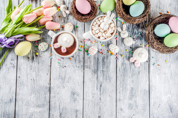 Easter funny kids food and drink concept, sweet hot chocolate with marshmallow bunny rabbits and easter eggs, wooden background copy space top view