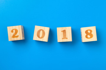 Year 2018. Wooden colorful alphabet blocks on blue background, flat lay, top view.