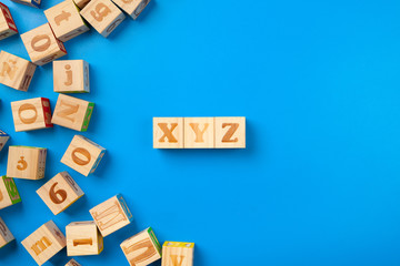 Fototapeta premium Wooden colorful alphabet blocks on blue background, flat lay, top view.