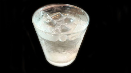 glass of water with ice on black background