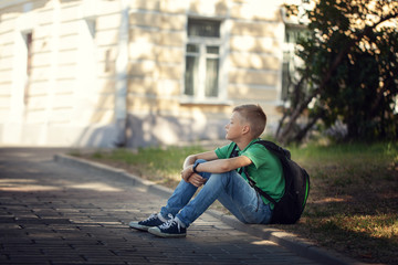 Obraz premium Sad alone boy sitting on road in the park outdoors.