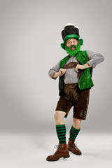 A smiling happy senior man in a leprechaun hat with beard at studio. He celebrates St. Patrick's...