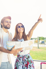 Happy young couple looking at the city map, traveling to new destinations