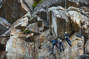 A group of climbers are hanging on a rock wall on a self-insurance. Tilt-Shift effect.
