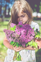 Little girl holding lilac flowers
