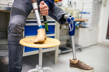 Disabled man working in amputee shop for production prosthetic extremity parts.