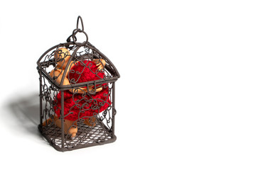 Action figure sitting in cage and holding red heart on white background. Concept of Love and imprisonment