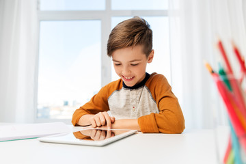 education, technology and learning concept - happy student boy with tablet pc computer and notebook learning at home