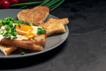 Breakfast toast with fried eggs and croutons on black background. Top view