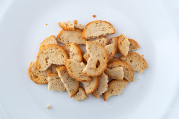 Top view of broken pieces of sesame round melba toast on a white plate.