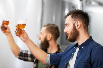 alcohol production, manufacture, business and people concept - men drinking and testing craft beer at brewery