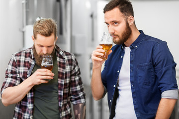 alcohol production, manufacture, business and people concept - men drinking and testing craft beer at brewery
