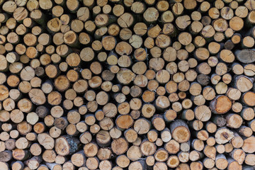 Background of dry chopped firewood logs stacked up on top of each other in a pile.